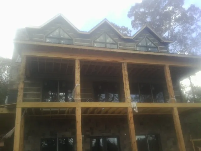 Dormers and porch framing on a large log home under construction — Roof Coating work by our crew in Berne