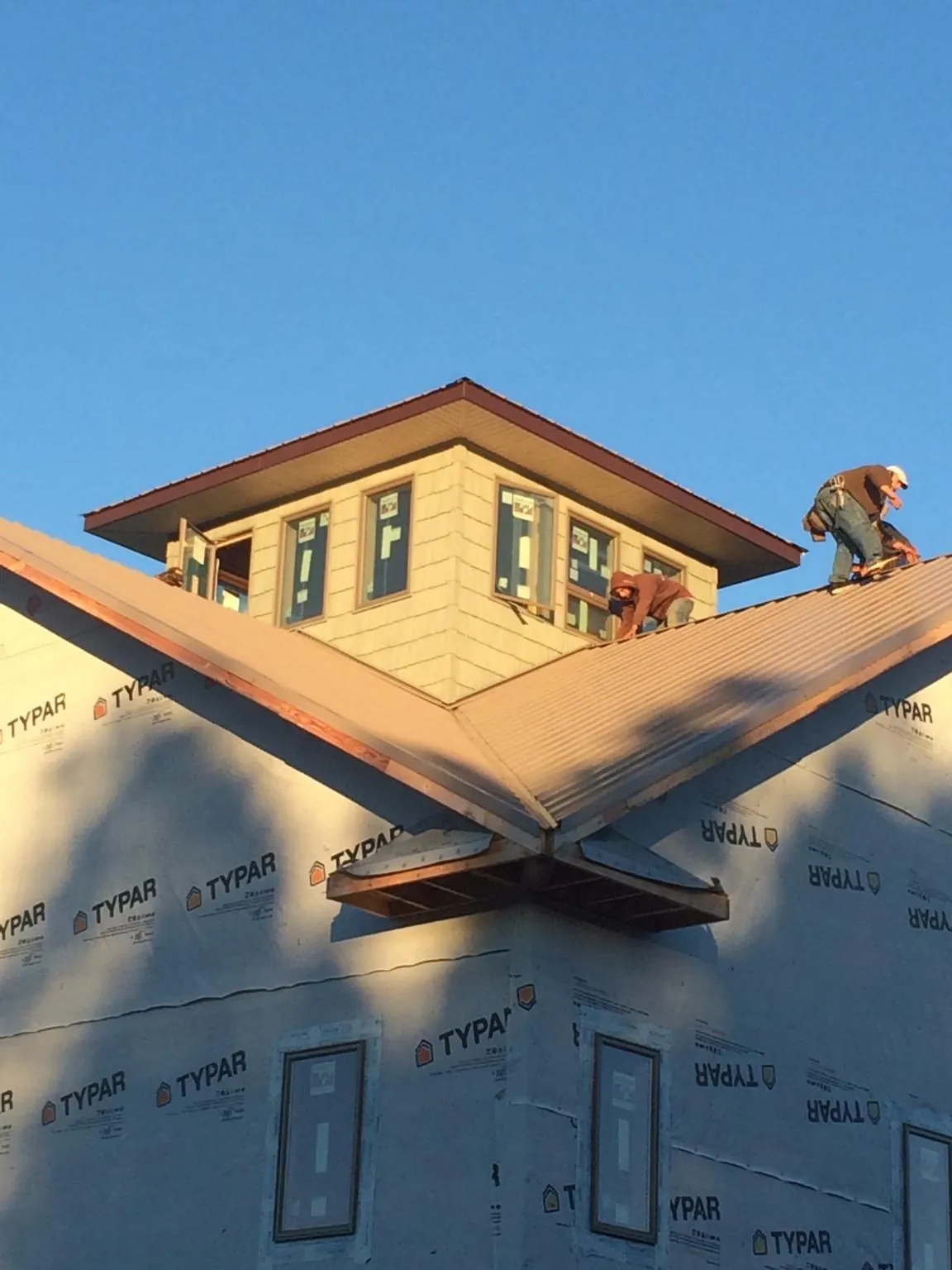 Roofers working around a rooftop cupola on a new metal roof at sunset — Roof Waterproofing in Berne by Roofing Brothers